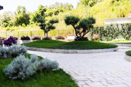a garden with two trees and a brick patio at Andor Luxury Hotel & Duplex in Durrës