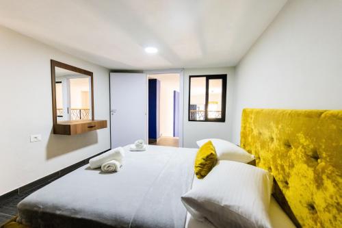 een slaapkamer met een groot bed en een gele bank bij Andor Luxury Hotel & Duplex in Durrës