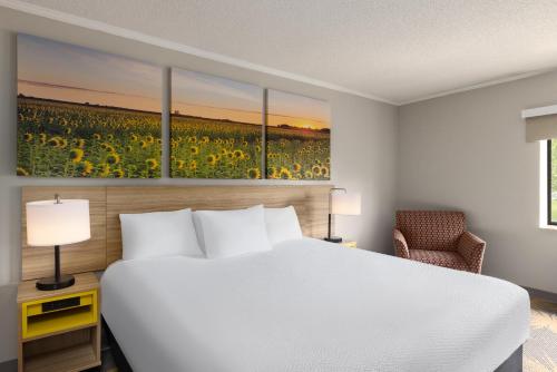 a hotel room with a bed and a field of sunflowers at Days Inn & Suites by Wyndham Kansas City - CHIEFS Stadium in Kansas City