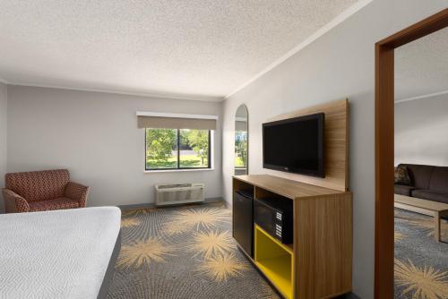a hotel room with a bed and a flat screen tv at Days Inn & Suites by Wyndham Kansas City - CHIEFS Stadium in Kansas City