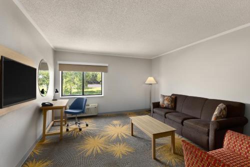 a living room with a couch and a table at Days Inn & Suites by Wyndham Kansas City - CHIEFS Stadium in Kansas City