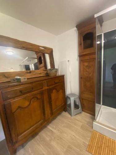 La salle de bains est pourvue d'une armoire en bois et d'un miroir. dans l'établissement Le Domaine Des Roses Normandie Foulognes, à Foulognes