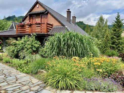a garden in front of a house with flowers at Górski Azyl w Soblówce in Sablówka