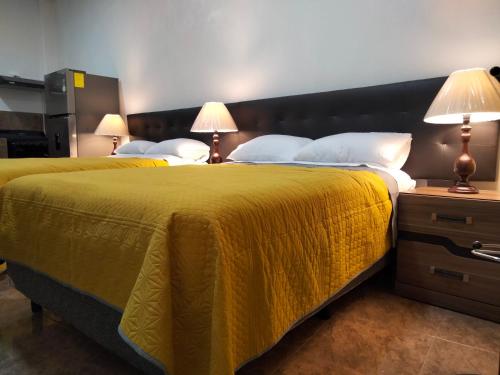 two beds in a hotel room with yellow blankets and pillows at Gran Tonantzin in San Martín de las Pirámides