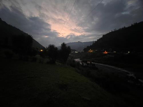 a view of a river in a field with a cloudy sky at La Casa Verde Eco Guest House in Baños
