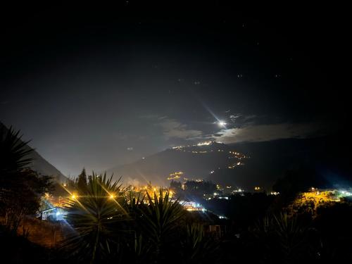 a view of a city at night with the moon at La Casa Verde Eco Guest House in Baños