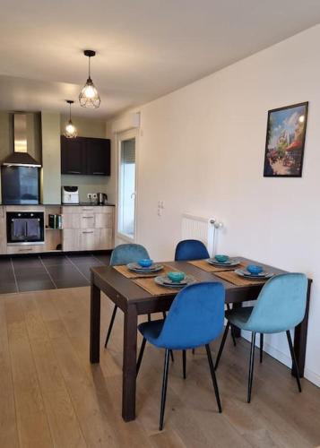 Il dispose d'une cuisine et d'une table à manger avec des chaises bleues. dans l'établissement Appartement Chic près de Paris - Parking & Terrasse, à Gennevilliers