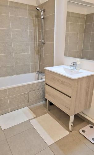 une salle de bain avec un lavabo, une baignoire et un miroir dans l'établissement Appartement Chic près de Paris - Parking & Terrasse, à Gennevilliers
