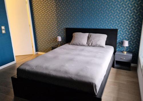une chambre avec un grand lit avec deux tables de nuit dans l'établissement Appartement Chic près de Paris - Parking & Terrasse, à Gennevilliers