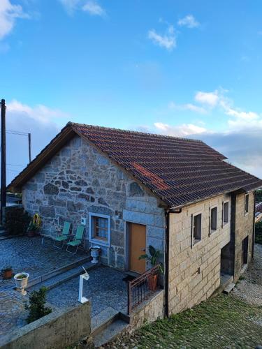 a small stone house with two chairs in front of it at Casa da Avó in Cetos