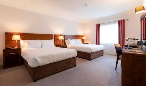 a hotel room with two beds and a desk at Schull Harbour Hotel & Leisure Centre in Schull
