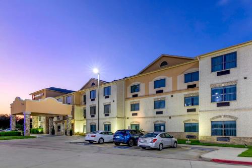 two cars parked in front of a building at Best Western Plus Burleson Inn & Suites in Burleson