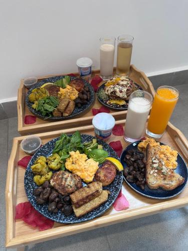 een tafel met drie borden eten en glazen sinaasappelsap bij Skyscraper 65 KL Highest Outdoor Bathtub Luxury Lavish Designer Suite Penthouse Lv65 in Kuala Lumpur