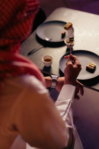 a person holding a fork with a piece of food on it at Radisson Blu Hotel Riyadh Convention and Exhibition Center in Riyadh