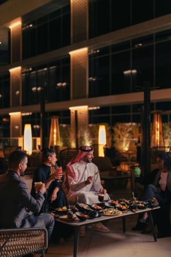 a group of people sitting around a table with food at Radisson Blu Hotel Riyadh Convention and Exhibition Center in Riyadh