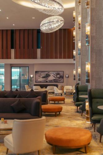 a waiting room with couches and tables and a chandelier at Radisson Blu Hotel Riyadh Convention and Exhibition Center in Riyadh