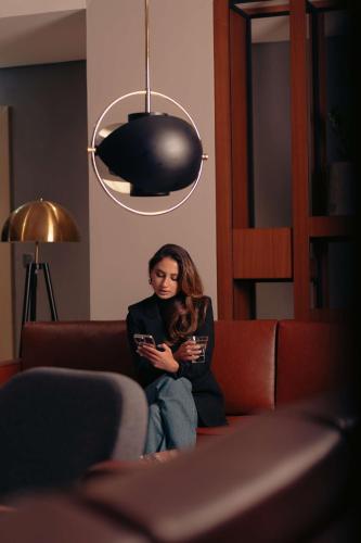 a woman sitting on a couch looking at her cell phone at Radisson Blu Hotel Riyadh Convention and Exhibition Center in Riyadh