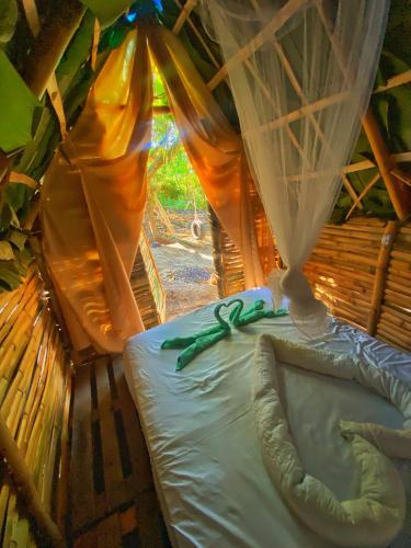 a room with a bed with a bow on it at Green House Chalé, hostel e pousada in Saquarema