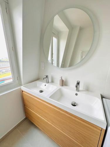 une salle de bain avec un lavabo blanc et un miroir dans l'établissement Cosy Sunny Saint-Denis, à Saint-Denis