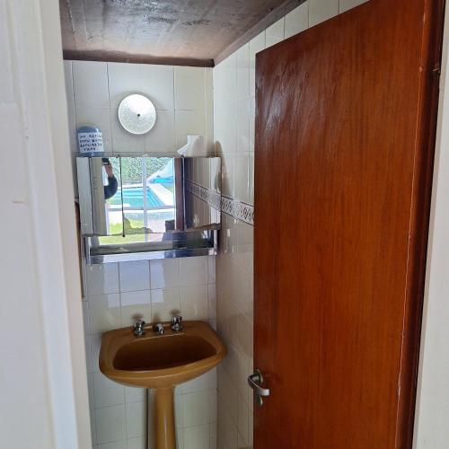 a bathroom with a sink and a wooden door at AMPLIO DEPARTAMENTO temporario in La Plata