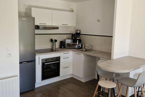 - une cuisine avec des appareils blancs, une table et des chaises dans l'établissement Appartement ensoleillé, à Les Sables-dʼOlonne