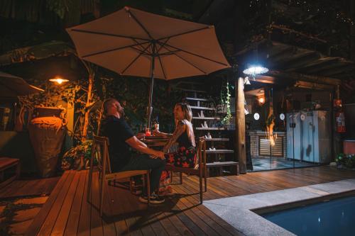 a man and woman sitting at a table under an umbrella at Pousada Arraial Inn in Arraial do Cabo