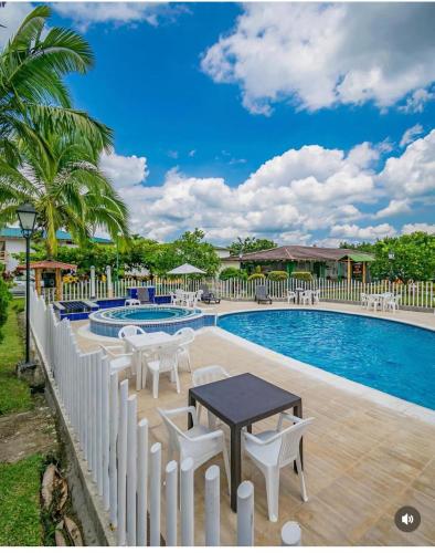 a pool with a table and chairs next to a fence at Hotel Campestre La Aldea Cabaña Pijao in Montenegro