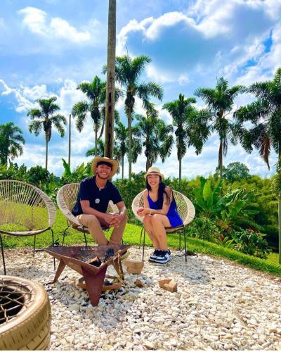 a man and woman sitting in chairs next to a fire at Hotel Campestre La Aldea Cabaña Pijao in Montenegro