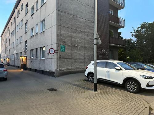 a white car parked on a street next to a building at Radiant BD Wejscie na kod in Gdynia