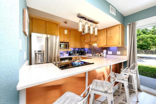 a kitchen with wooden cabinets and a counter with chairs at Cool Azul 3 Community Pools Central Destin in Destin