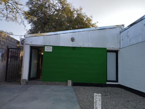una porta verde del garage su un edificio bianco di Takú Huasi a La Rioja