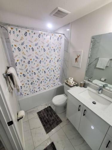 a bathroom with a shower curtain with a toilet and a sink at Charming 2-Bedroom Basement Oasis Sleeps 5,Size-150sqm, Netflix, family friendly in Edmonton