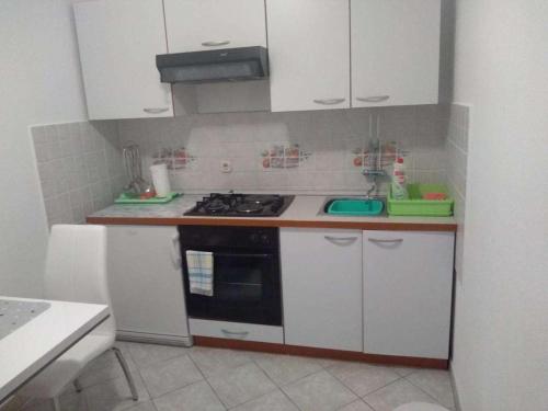 une petite cuisine avec une cuisinière et des armoires blanches dans l'établissement Apartments with parking space Kneza, Korcula - 23421, à Pupnat