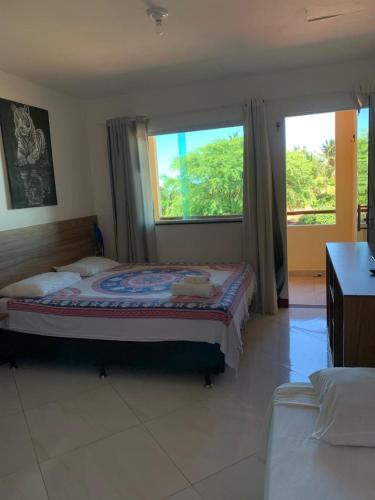 a bedroom with a bed and a large window at Chalés Pulo do Gato in Canoa Quebrada
