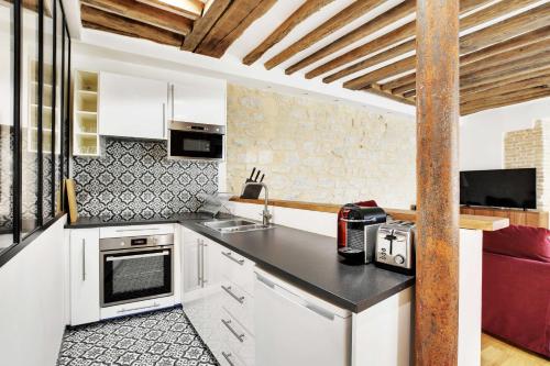 une cuisine avec des armoires blanches et un comptoir dans l'établissement Appartement Chic au Cœur du 9ème 2 chambres 6P, à Paris
