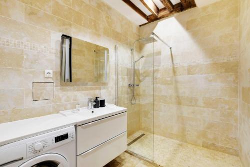 La salle de bains est pourvue d'un lave-linge et d'une douche. dans l'établissement Appartement Chic au Cœur du 9ème 2 chambres 6P, à Paris