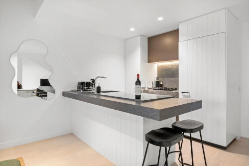 a kitchen with white walls and a counter with stools at Modern, Luxury Retreat with Gym and Pool in Melbourne
