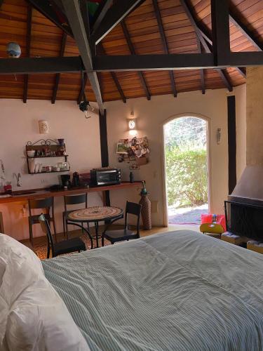 Un dormitorio con una cama y una mesa y una cocina. en Espaço arborizado com Casa e Chalé em bairro nobre de Monte Verde, en Camanducaia