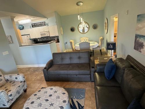 a living room with two brown couches and a kitchen at Park Avenue Beauty in Foley