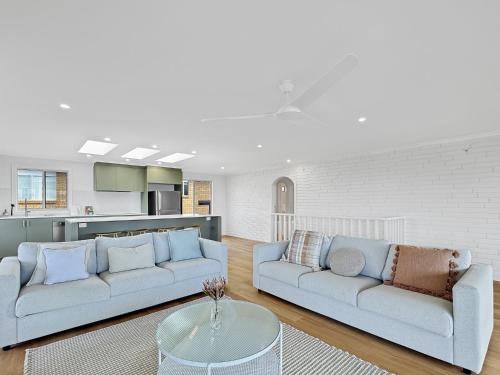 a living room with two couches and a table at 2-Bed Beach Haven with Garden & Alfresco Dining in Malua Bay