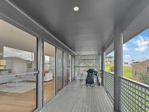 a porch with a stroller sitting on a balcony at 2-Bed Beach Haven with Garden & Alfresco Dining in Malua Bay
