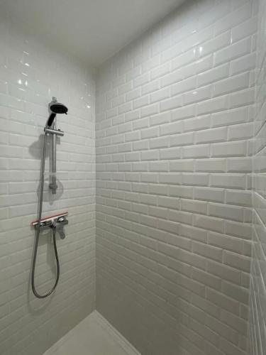 La salle de bains blanche est pourvue d'une douche avec un pommeau de douche. dans l'établissement Le terra apaisant - 5 min de la gare, à Tours