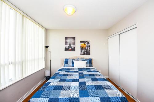 a bedroom with a bed with a blue and white checkered blanket at PlanURstay in Mississauga