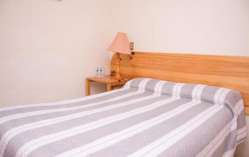 a bedroom with a bed with a wooden headboard and a lamp at Hotel Miramar in San Cristóbal de Las Casas