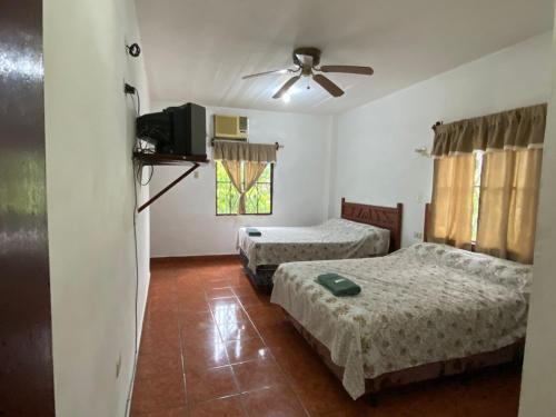 a room with two beds and a ceiling fan at Hotel Inn El Guanaco in San Miguel