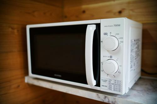 a white microwave oven sitting on top of a counter at 奄美ゲストハウス矢之脇町-Amami Guesthouse Yanowakicho- in Amami