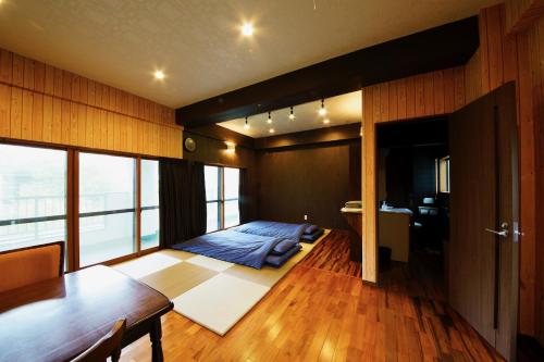 a bedroom with a bed and a wooden floor at 奄美ゲストハウス矢之脇町-Amami Guesthouse Yanowakicho- in Amami