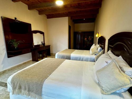 a hotel room with two beds and a television at Parador Margarita in San Crist&oacute;bal de Las Casas