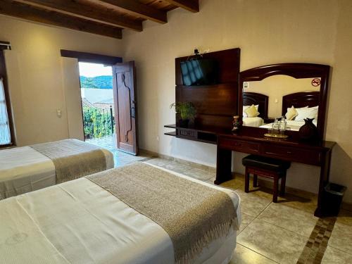 a bedroom with two beds and a mirror and a desk at Parador Margarita in San Cristóbal de Las Casas
