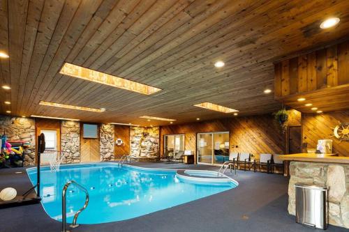 a large swimming pool in a room with a wooden ceiling at New Bensenville Home by O'Hare Airport with Indoor Pool, Sauna, and Arcade in Bensenville